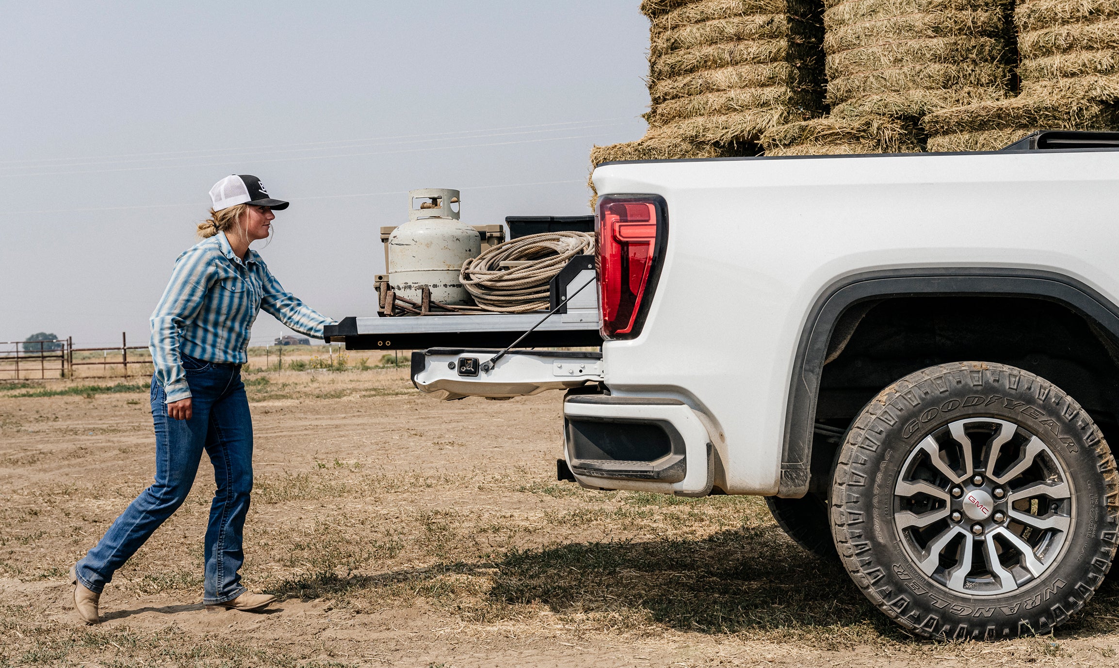 Rancher extending a DECKED CargoGlide loaded with a propane tank, rope, and equipment.