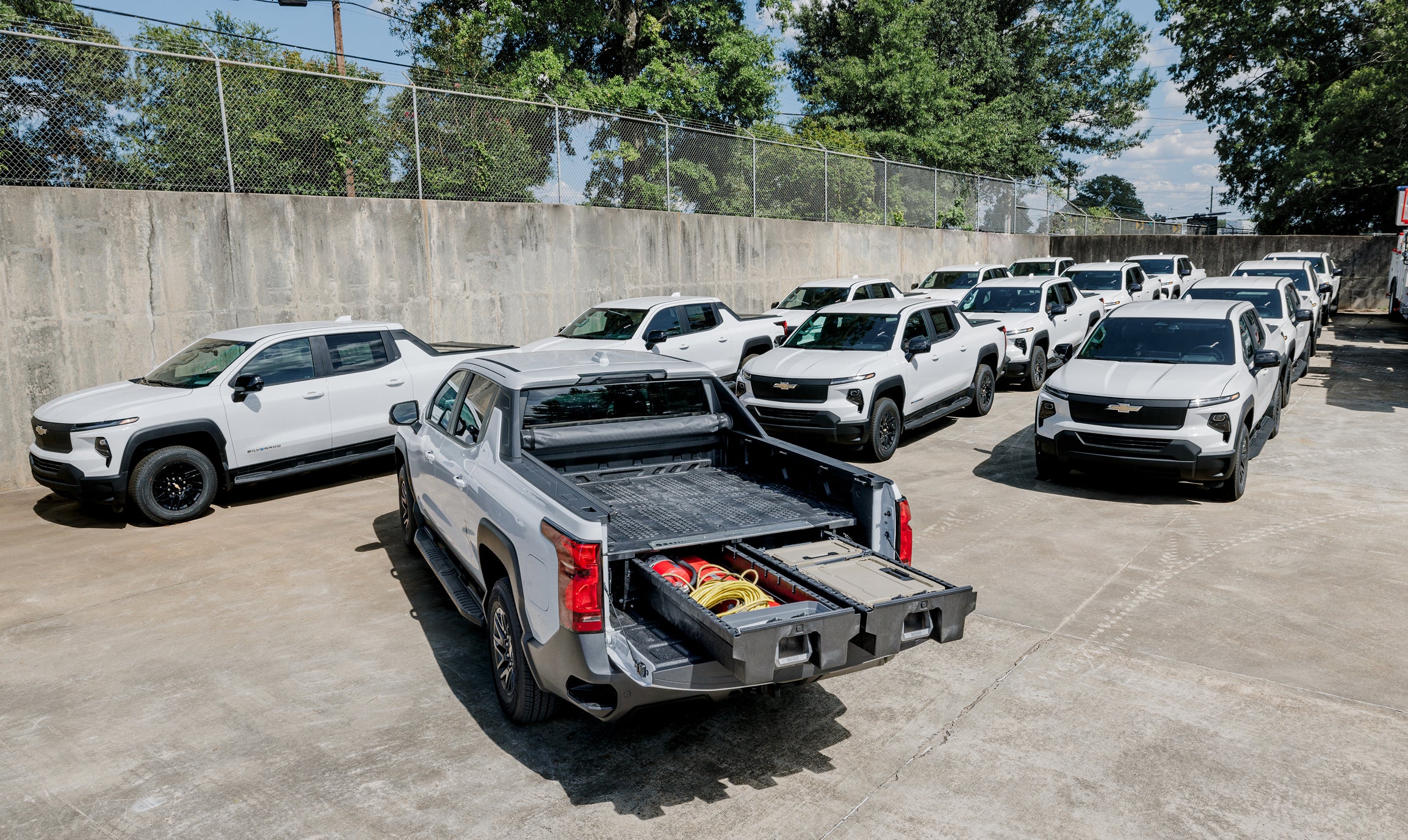 Fleet of work trucks with one pickup displaying an open DECKED Drawer System for organized equipment storage.