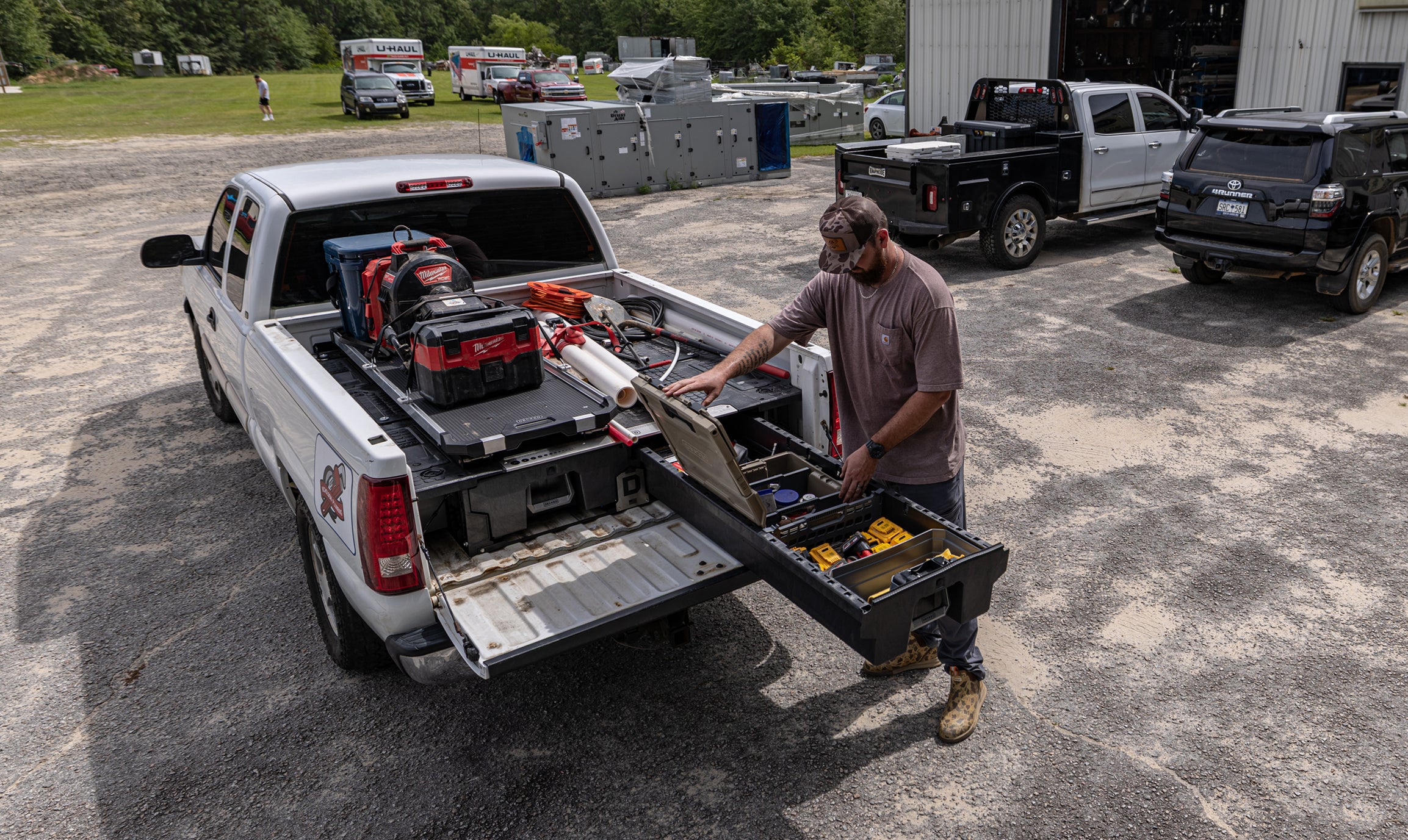 Contractor accessing organized power tools from a DECKED Drawer System beneath a CargoGlide.