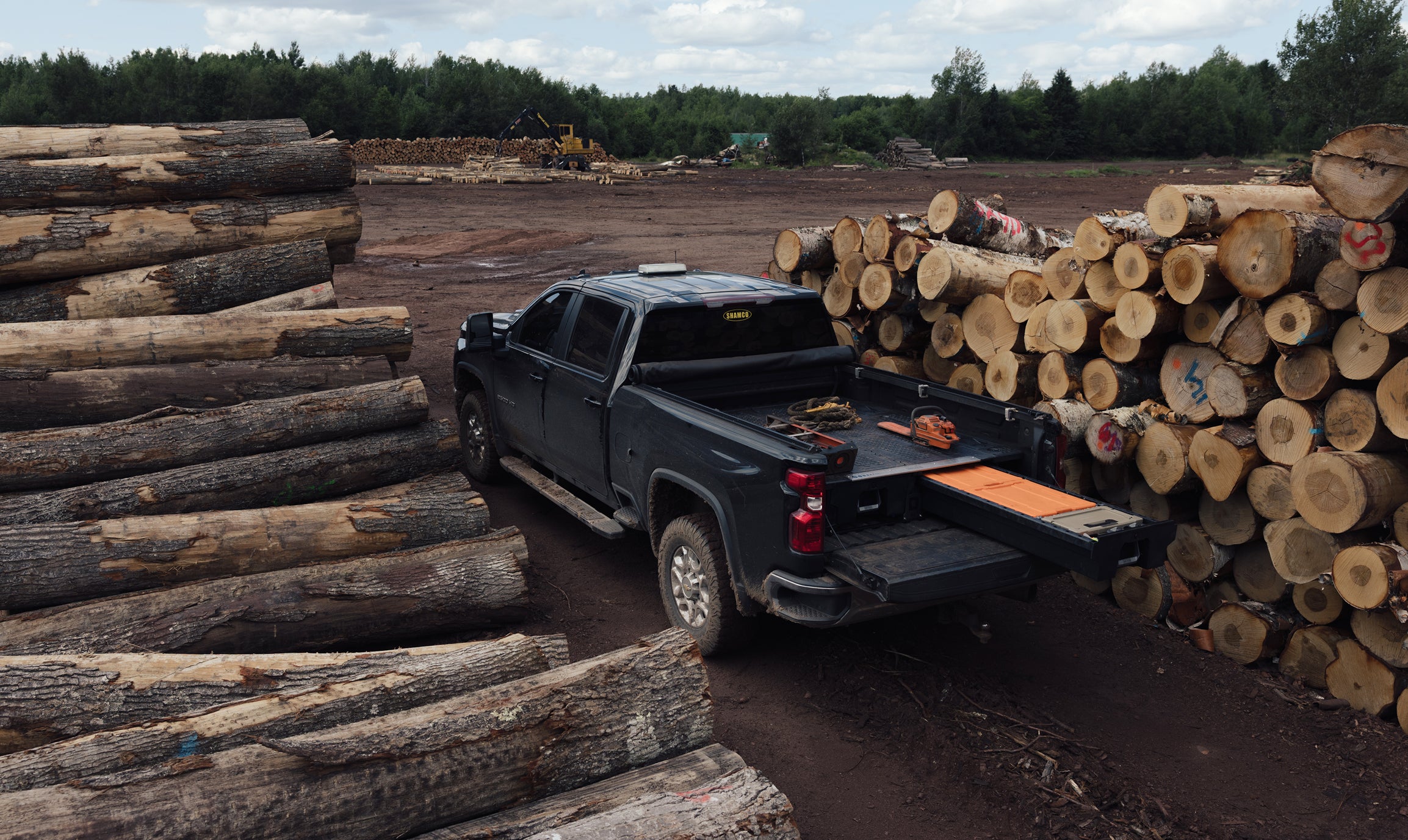 DECKED Drawer System open in a pickup truck bed surrounded by stacks of timber at a logging site.