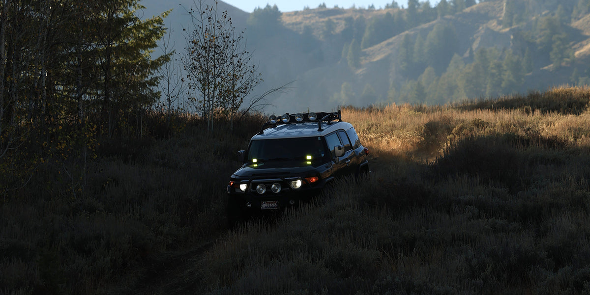 Toyota FJ Cruiser driving through a mountain landscape at dusk.