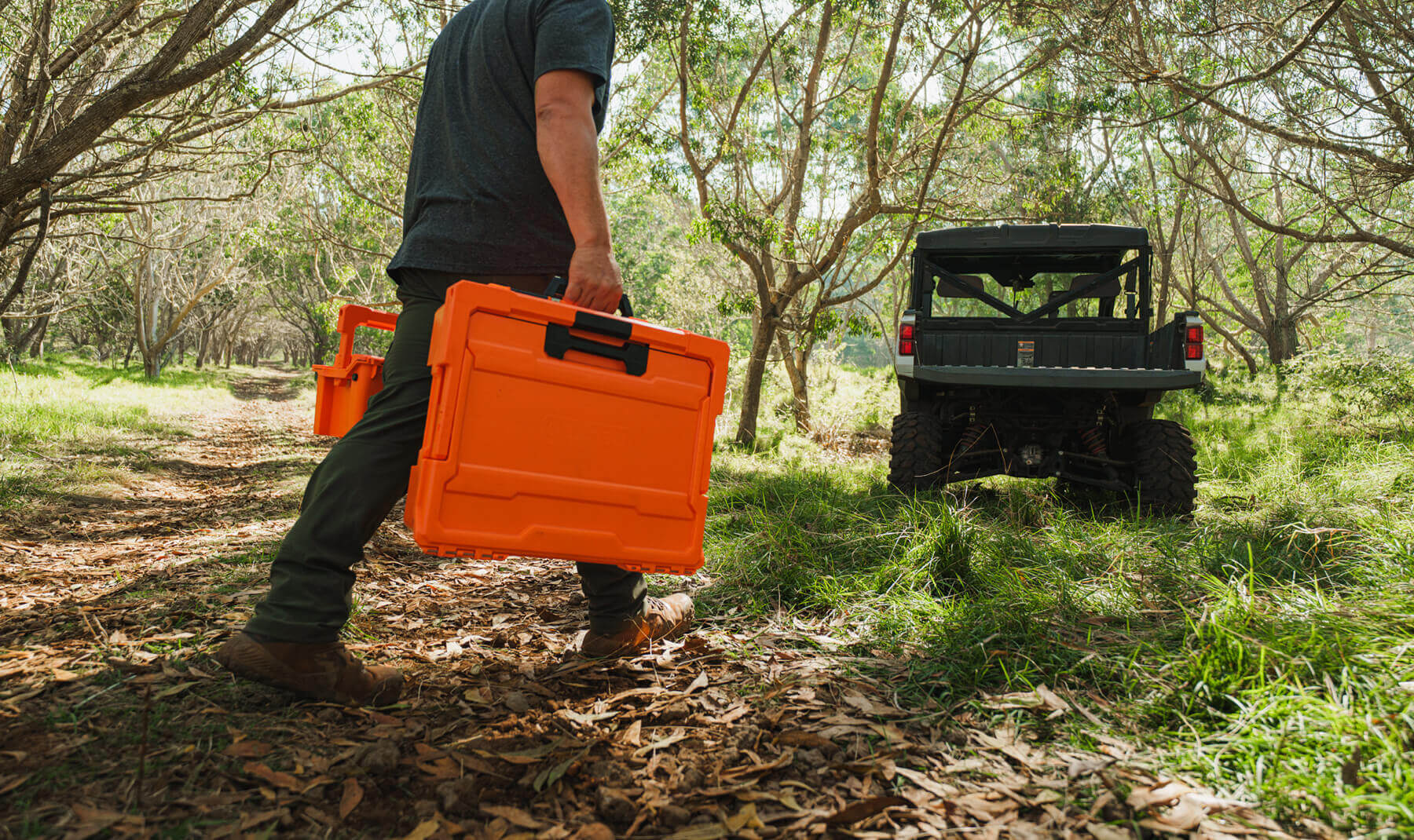 A man carrying the Blaze Orange Sixer and Halfrack D-co cases. The orange of the cases pops in the woods, making them easy to spot.