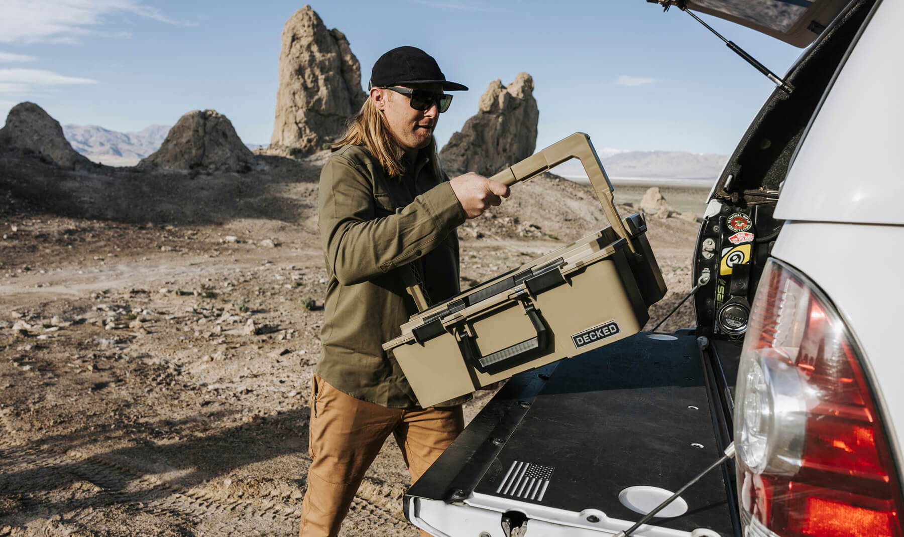 A man pulling his Desert Tan Halfrack out of the bed of his truck. He uses his D-co Cases to keep his camp kitchen organized while overlanding out in the Utah desert.