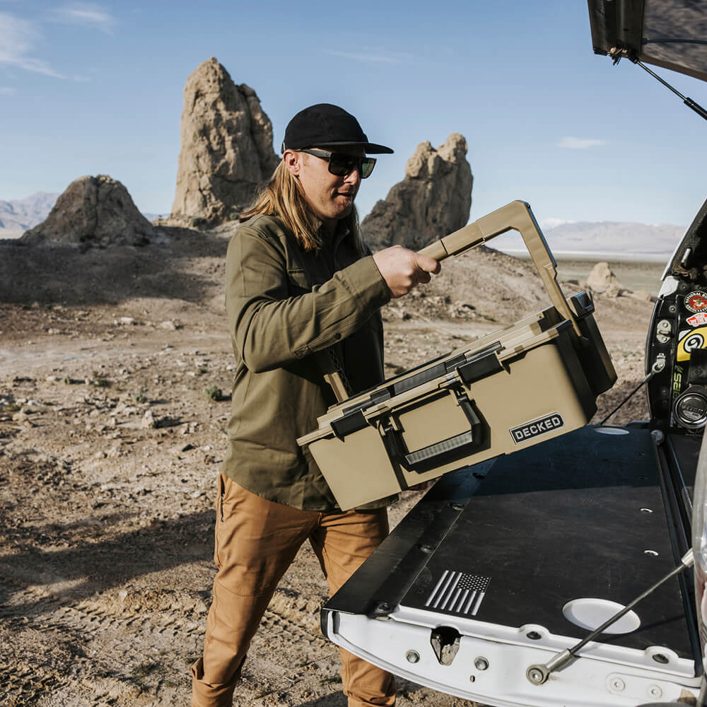 A man pulling his Desert Tan Halfrack out of the bed of his truck. He uses his D-co Cases to keep his camp kitchen organized while overlanding out in the Utah desert.