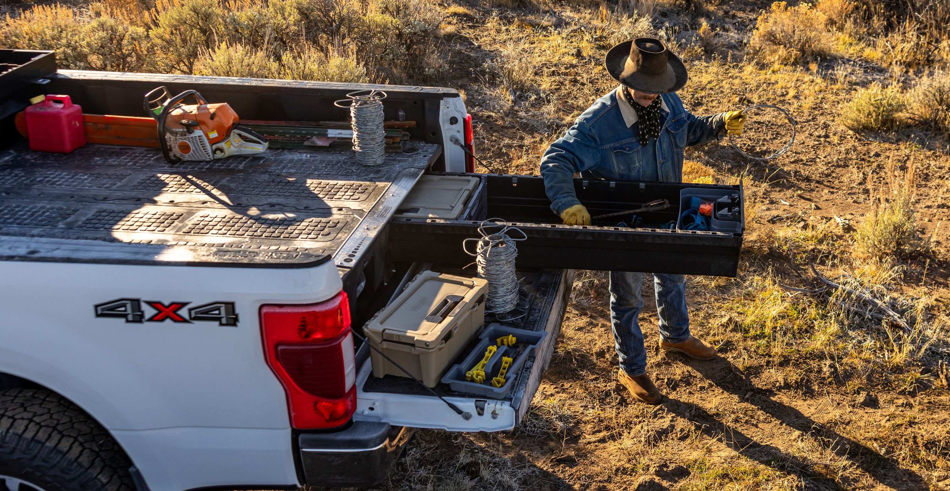 Rancher retrieving fencing wire from a DECKED Drawer System beside a pickup truck.