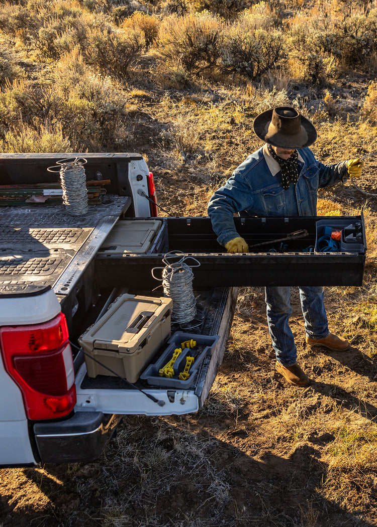 Rancher retrieving fencing wire from a DECKED Drawer System beside a pickup truck.