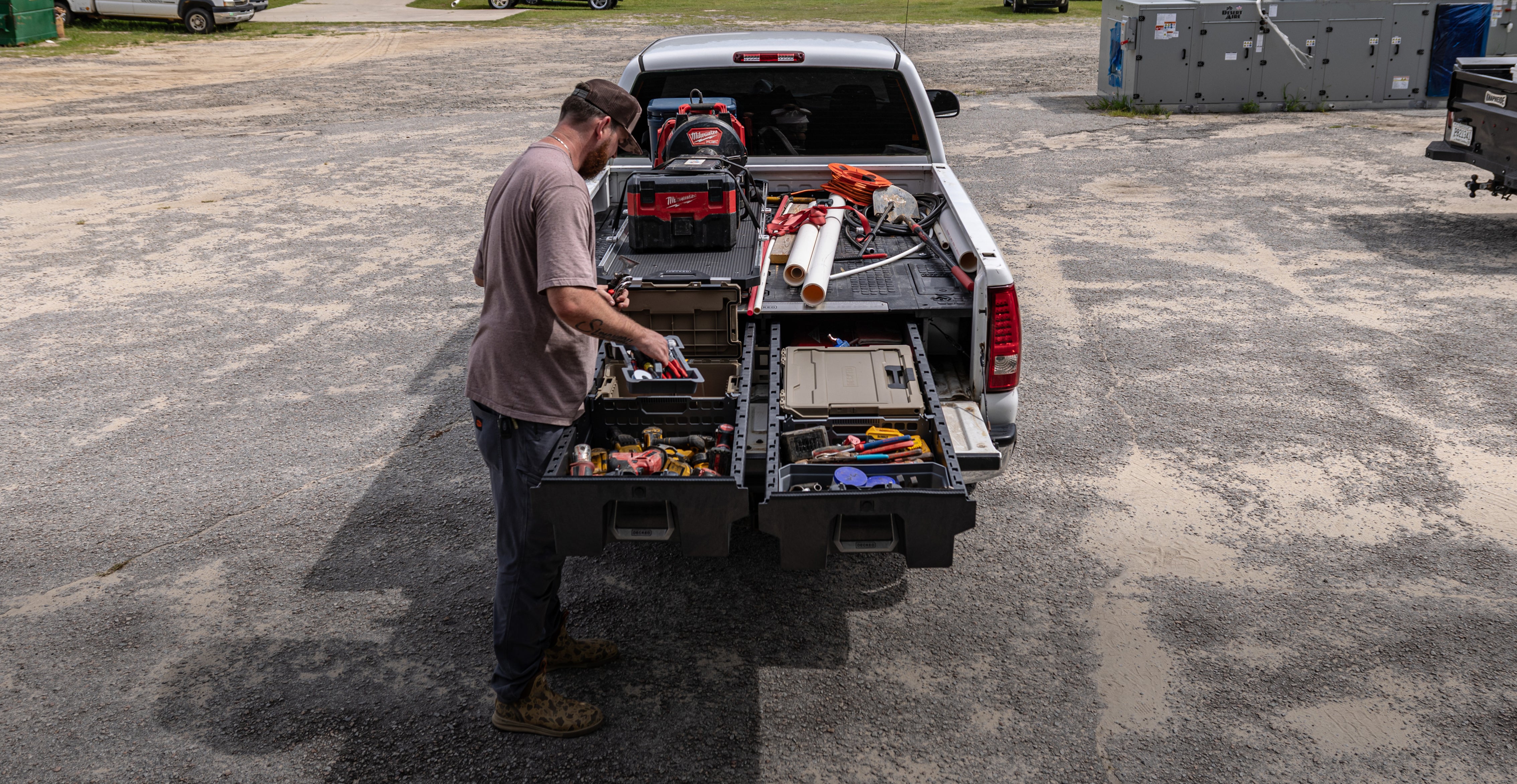  Plumber accessing organized power tools and a DECKED case from a Drawer System beneath a CargoGlide.