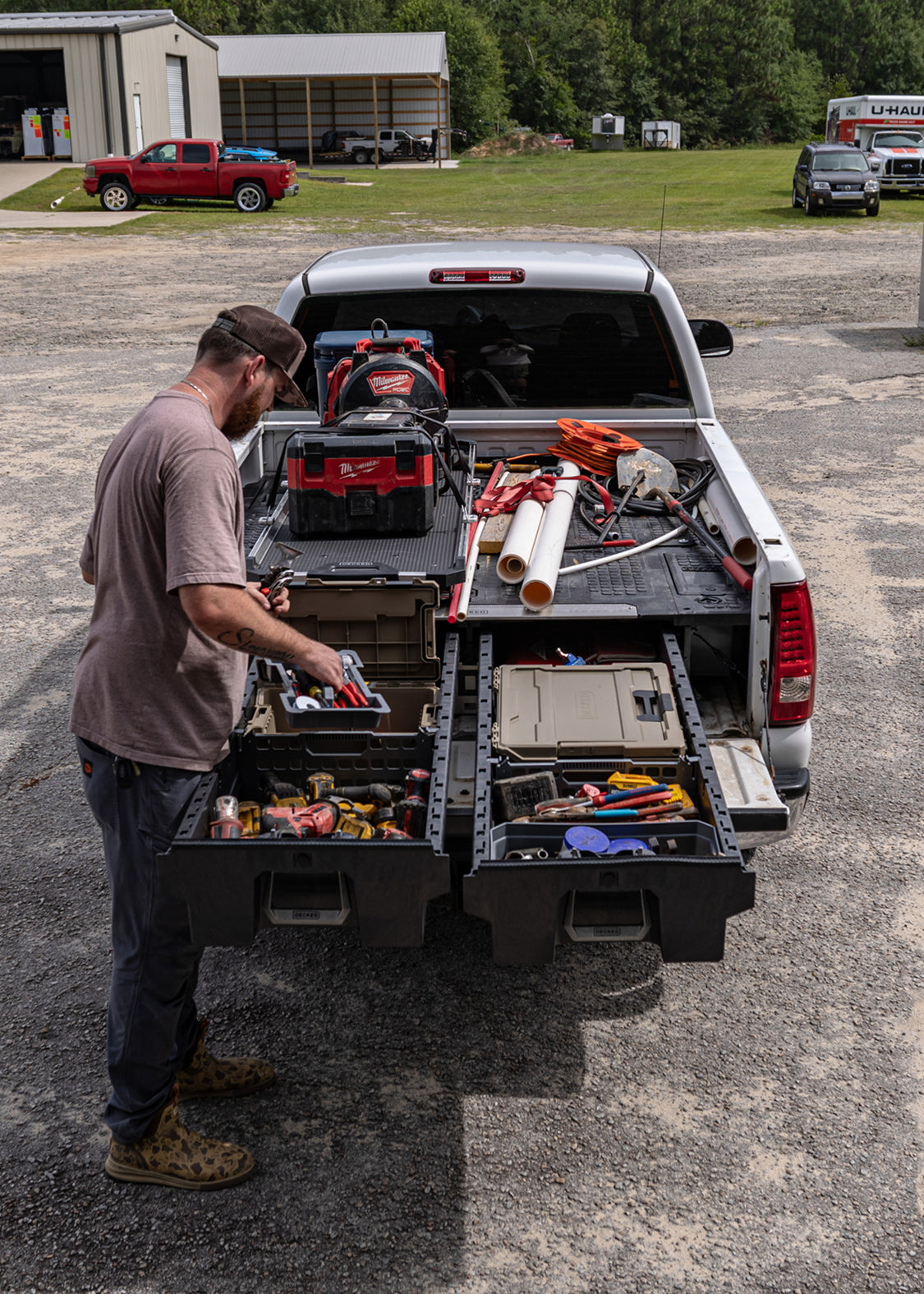 Plumber accessing organized power tools and a DECKED case from a Drawer System beneath a CargoGlide.
