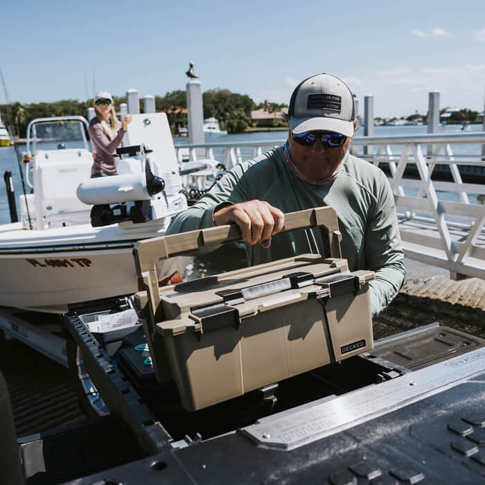 Man unloading a tan Sixer 16 from a Drawer System onto a boat on a dock.