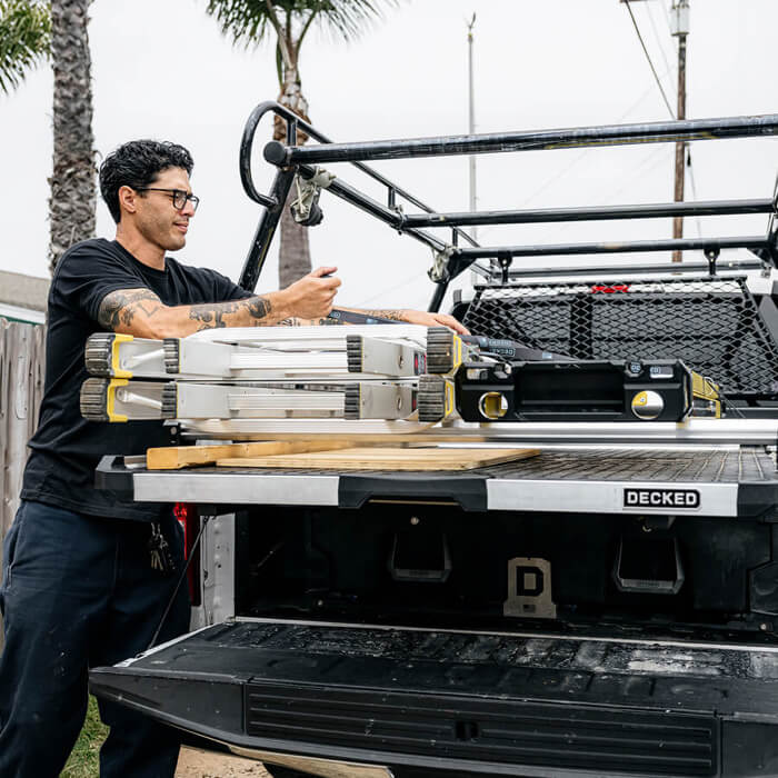 Man strapping a ladder onto his CargoGlide for Drawer System in his truck bed.