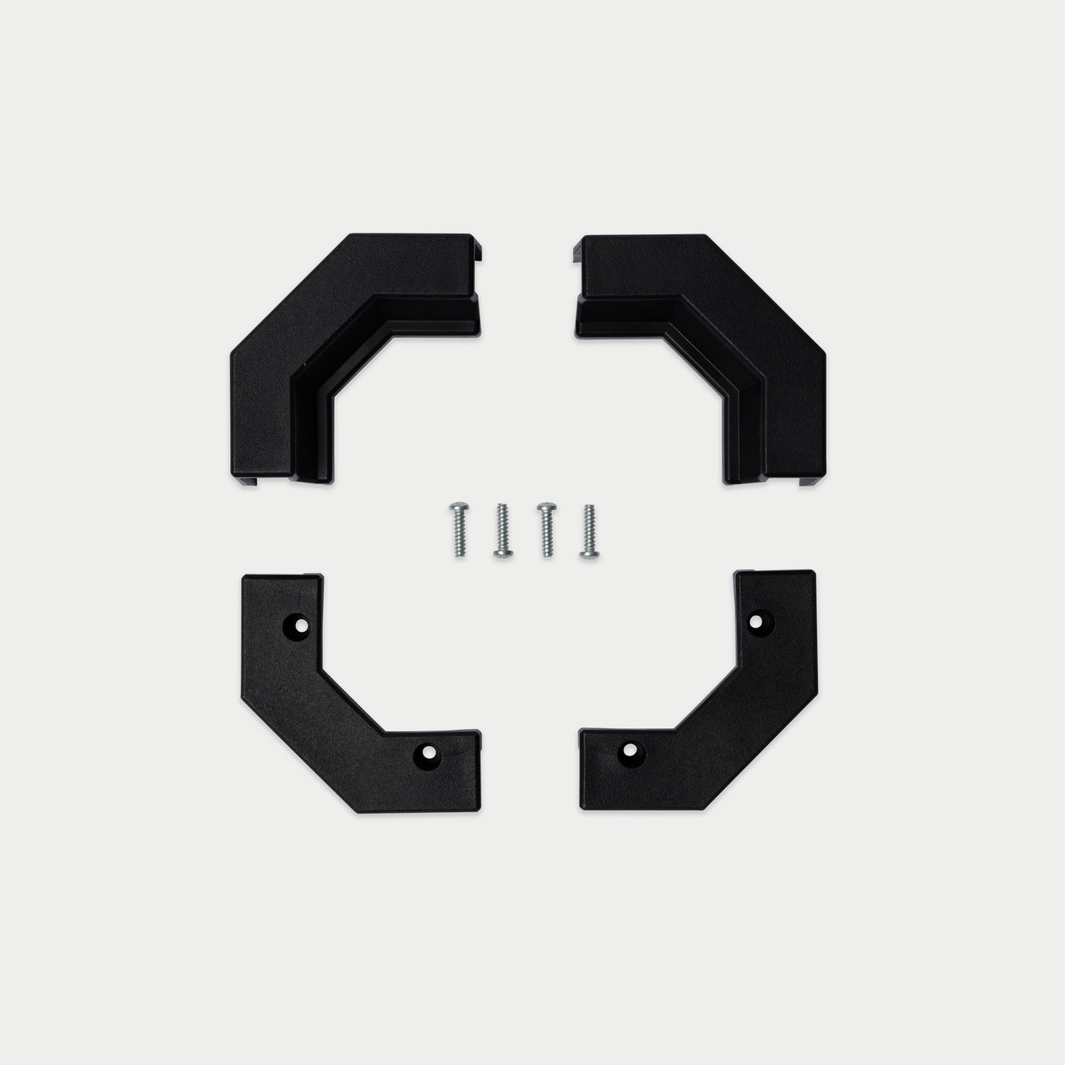 Four black metal bracket pieces arranged in a square with four small silver screws in the center, photographed on a light gray background.