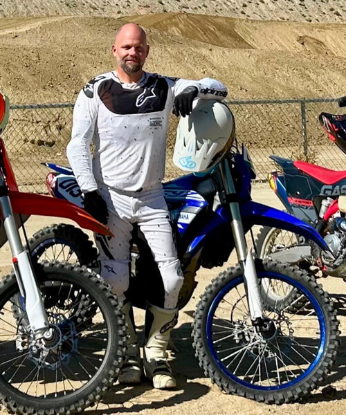 A man standing next to his dirt bike.