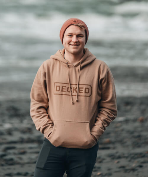 Oliver smiling in a DECKED sweatshirt, oceanside.