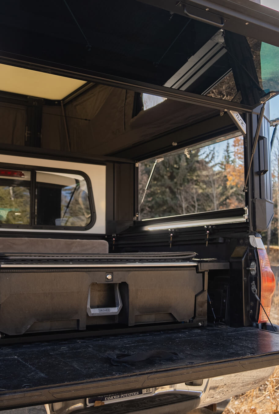 Open cargo bed of a vehicle with a black cover and interior, set against a natural background.