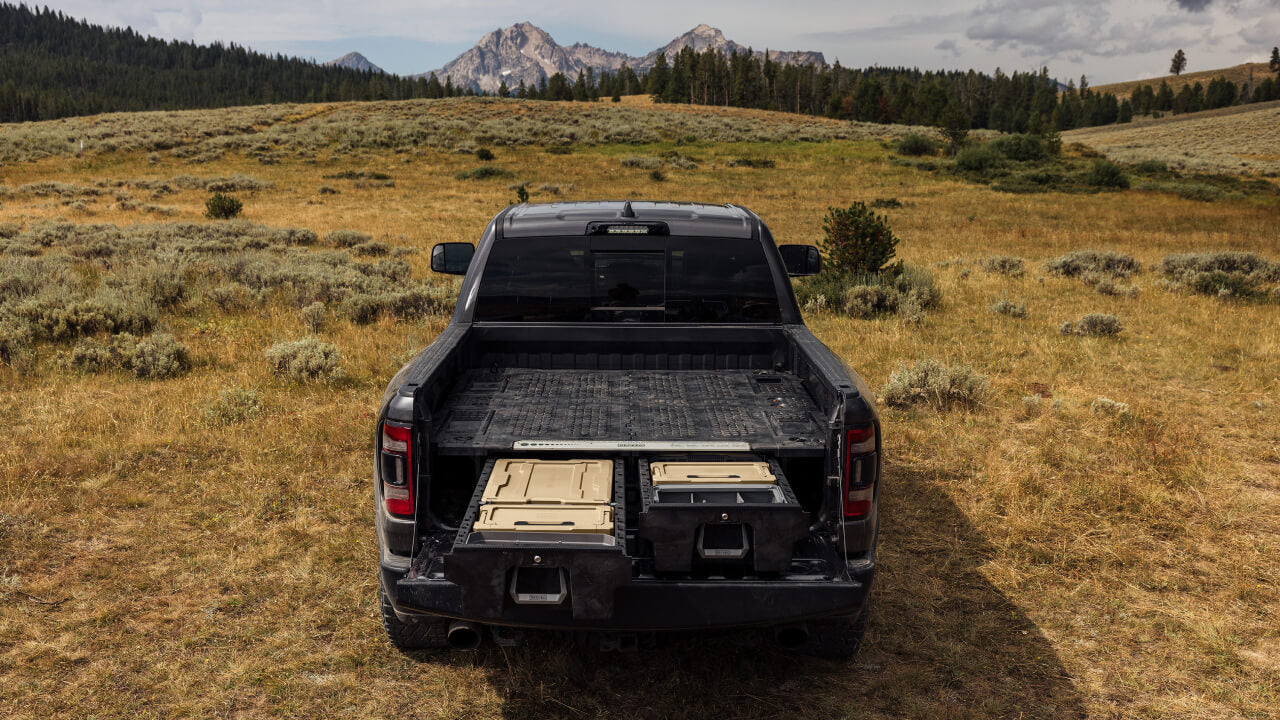 back of truck with a drawer system open in a field with mountains in the background