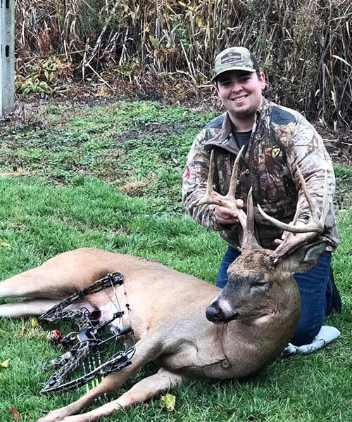 Man posing with a deer after hunting