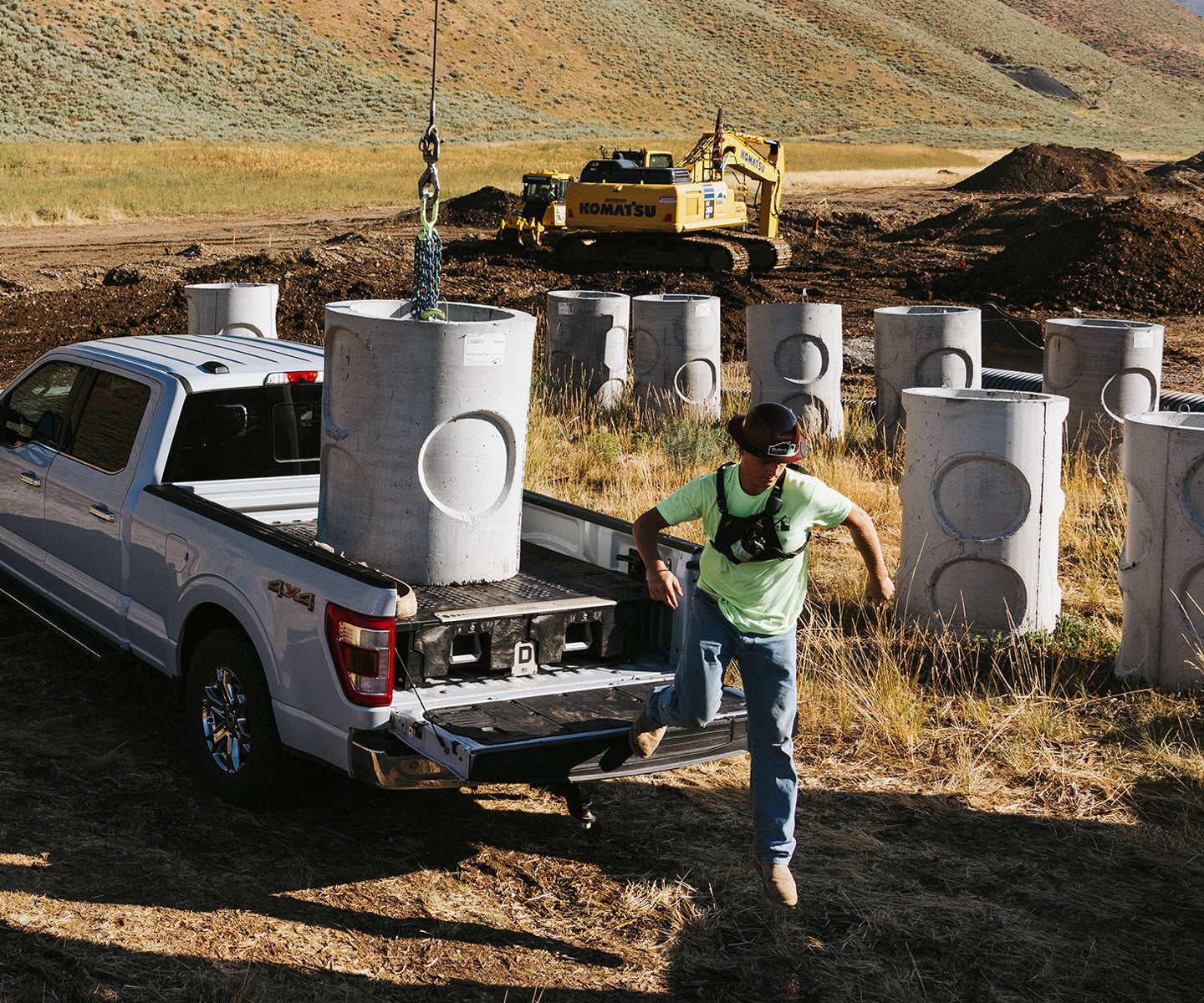 A man climbing down from his tailgate after craning a cement piling onto the top of his DECKED Drawer System.