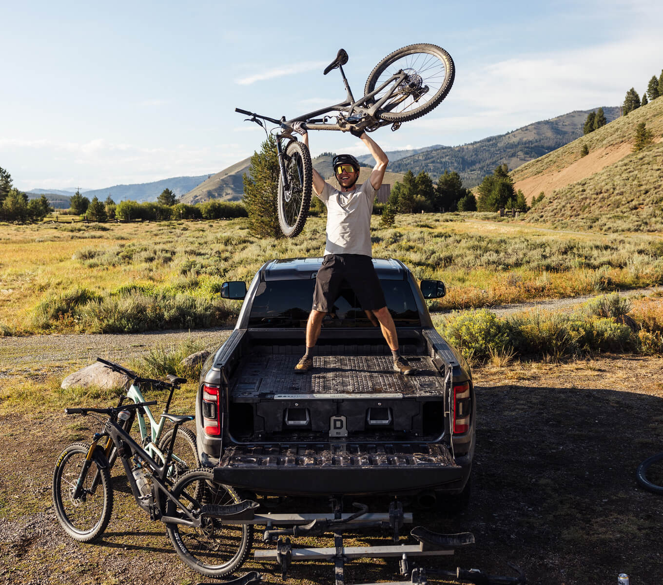 A man standing on his Drawer System, holding his mountain bike above his head triumphantly. 