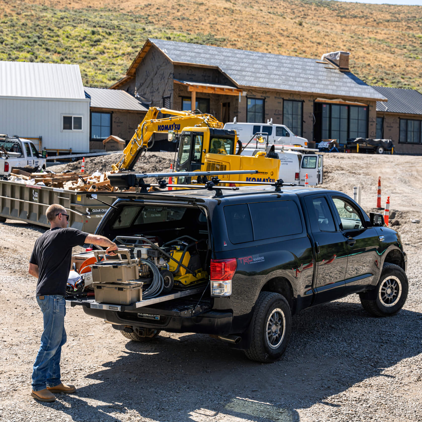 A man working on a residential construction site pulling gear off of his CargoGlide slide system that is loaded down with large equipment and D-co cases holding miscellaneous tools.