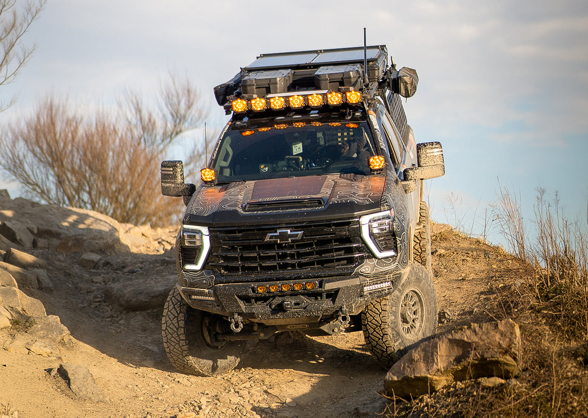Black chevy overlanding truck on a mountain road.