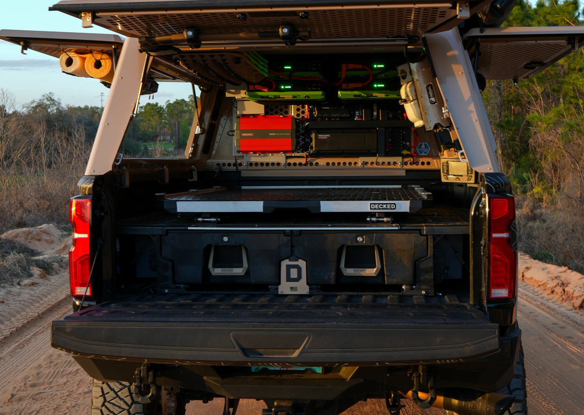 Open truck canopy with a DECKED drawer system, slide-out work surface, onboard power system, and organized storage for overlanding gear.