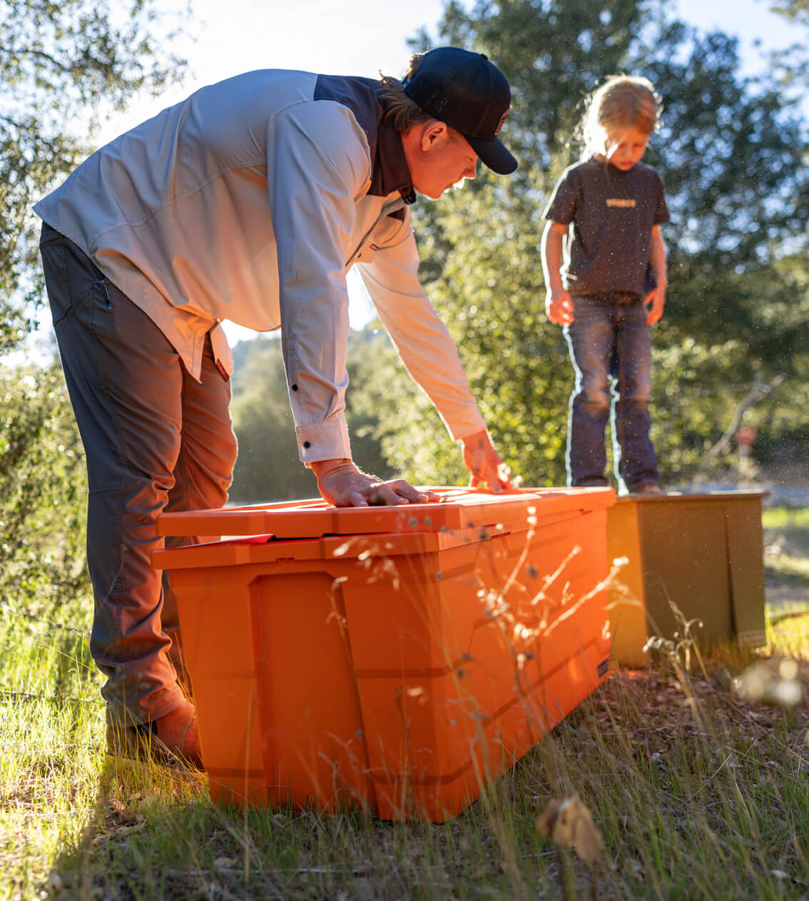 Man and child interacting with large orange Payloader 133 storage containers outdoors