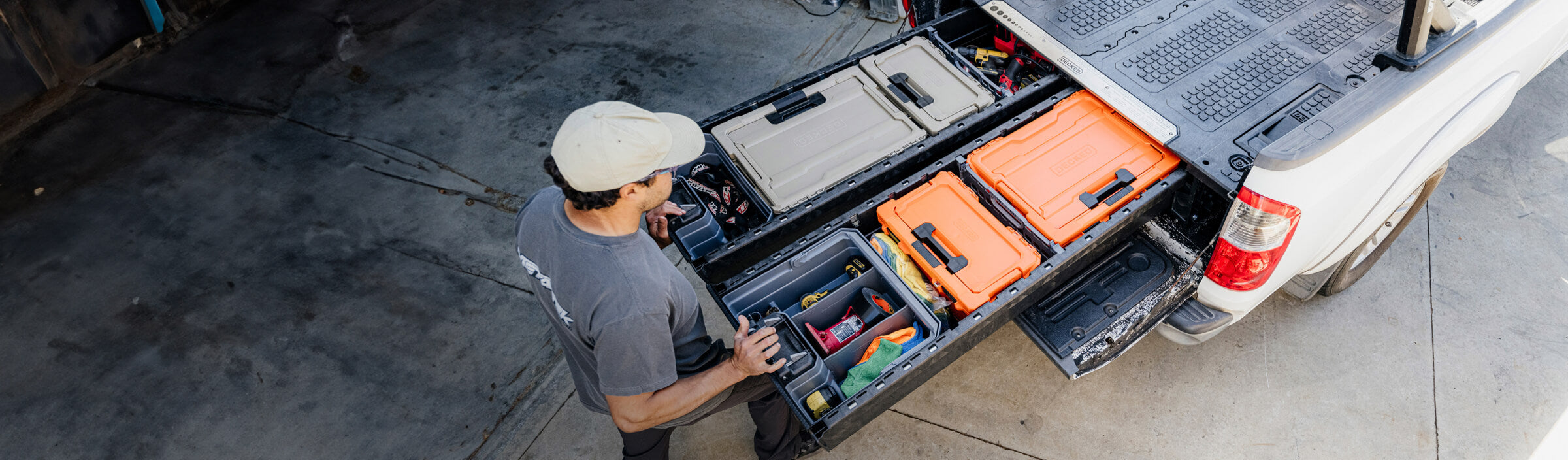 Person organizing tools in a truck bed with open toolboxes.