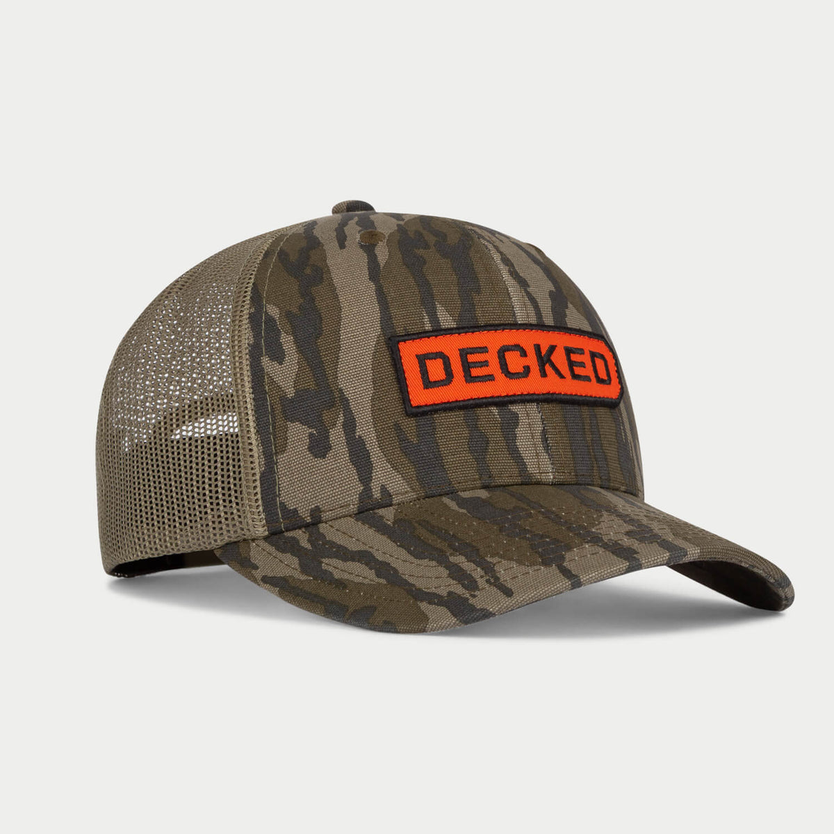 [H0777-LOGO-CAMO] Three-quarter view of a Mossy Oak Bottomland camo trucker hat with an orange DECKED patch on the front panel.