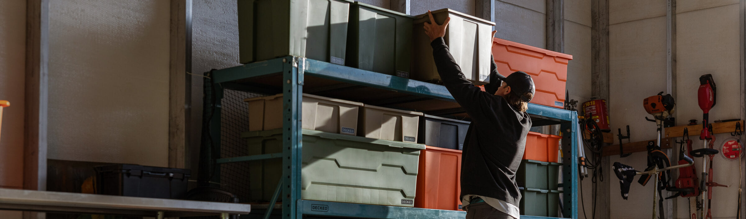 Person organizing ultra-rugged Payloader storage bins on a shelf in a garage.