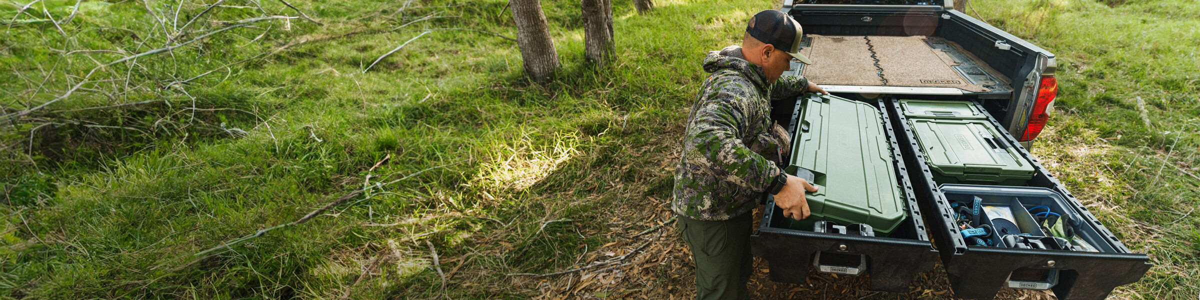 A man in a camo jacket pulling a Ranger Green D-co case out of his DECKED Drawer System.