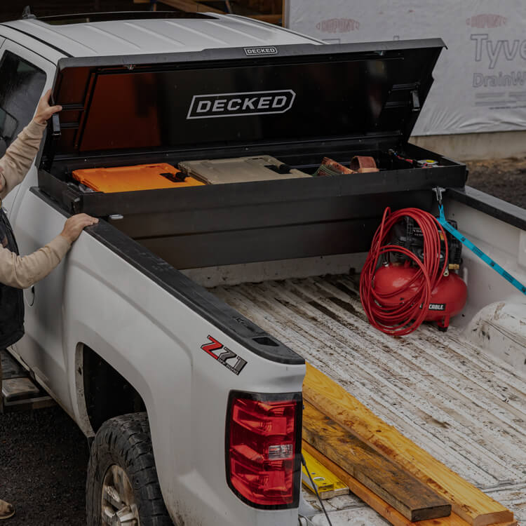 Worker opening a DECKD black Tool Box containing D-CO cases and other accessories.