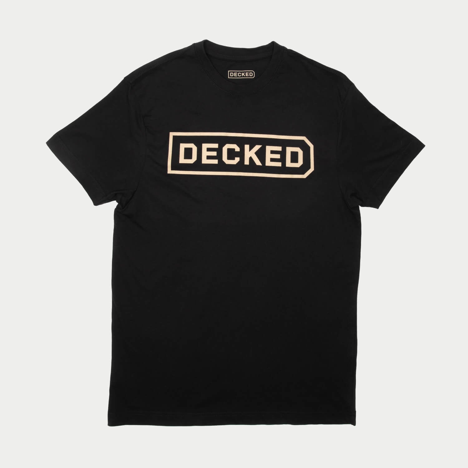 [T0001-DECK-BLK, T0002-DECK-BLK, T0003-DECK-BLK, T0004-DECK-BLK, T0005-DECK-BLK, T0006-DECK-BLK] Black t-shirt with 'DECKED' logo on a light gray background