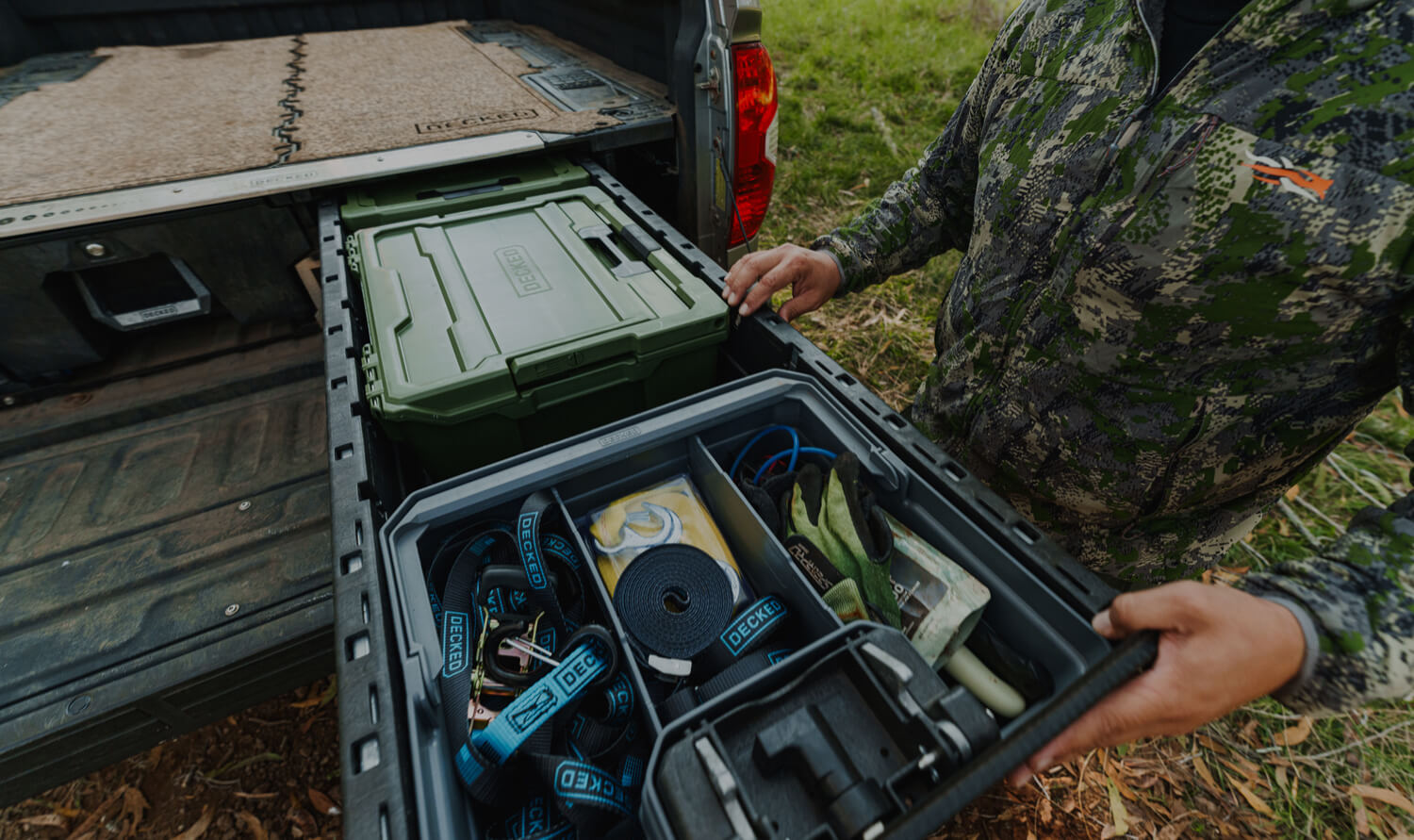 A hunter organizing hunting gear in his DECKED Drawer System and storage cases inside his truck bed.