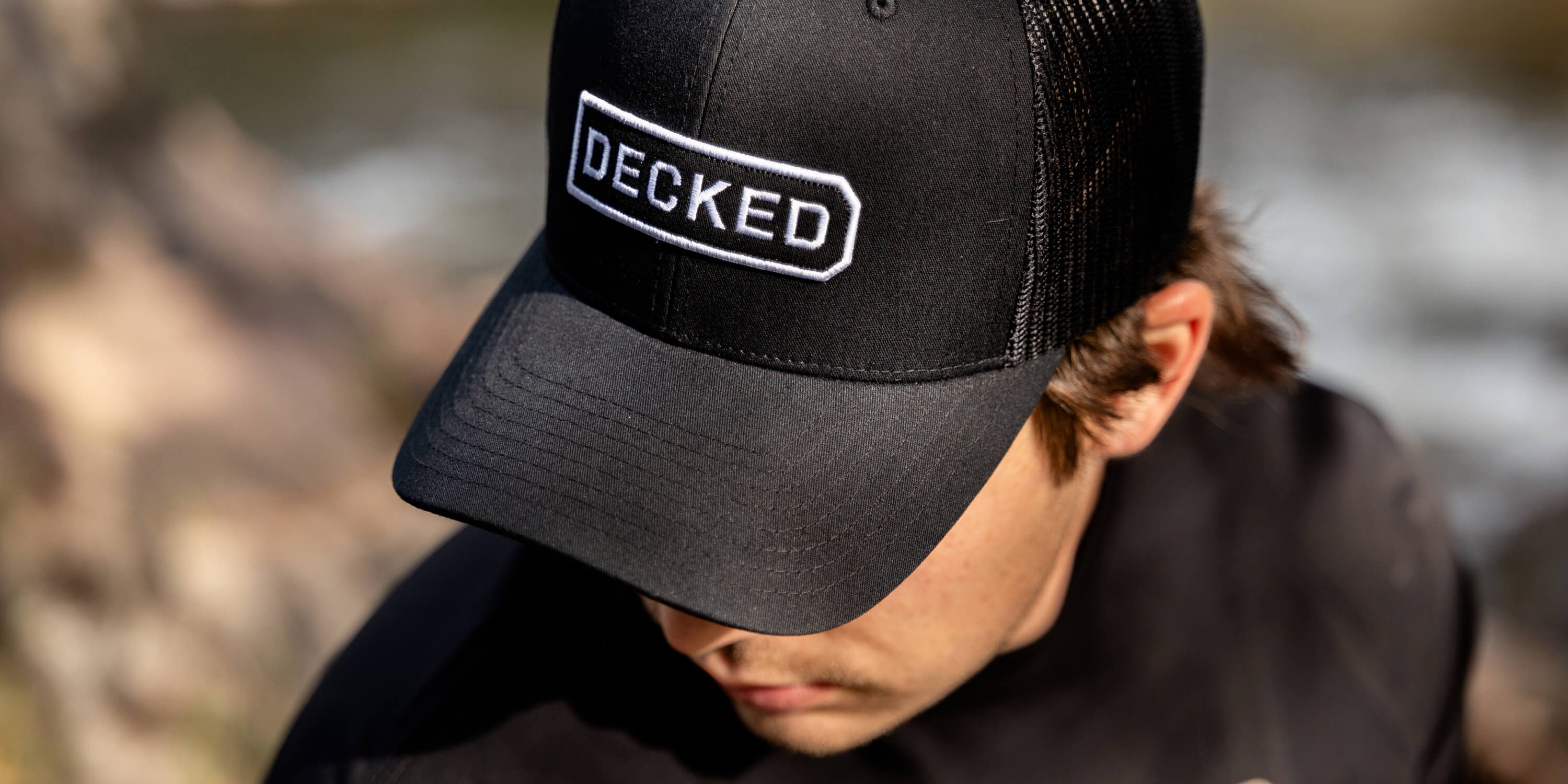 Person wearing a black cap with 'DECKED' logo outdoors