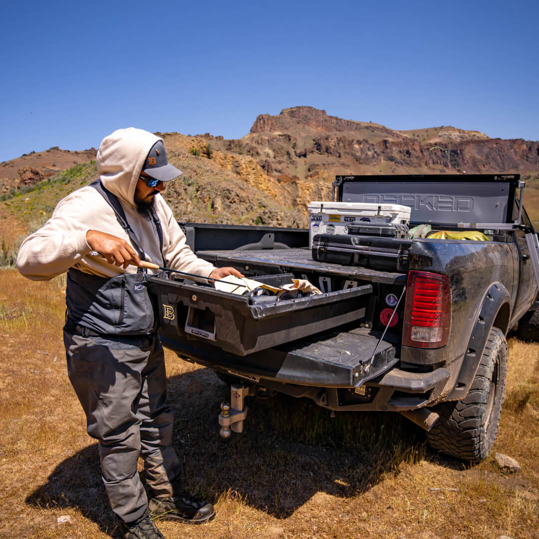 Backside view of a Drawer System installed in an 8 foot truck and a DECKED Tool Box filling the cabside gap. Fly fisherman accessing his gear