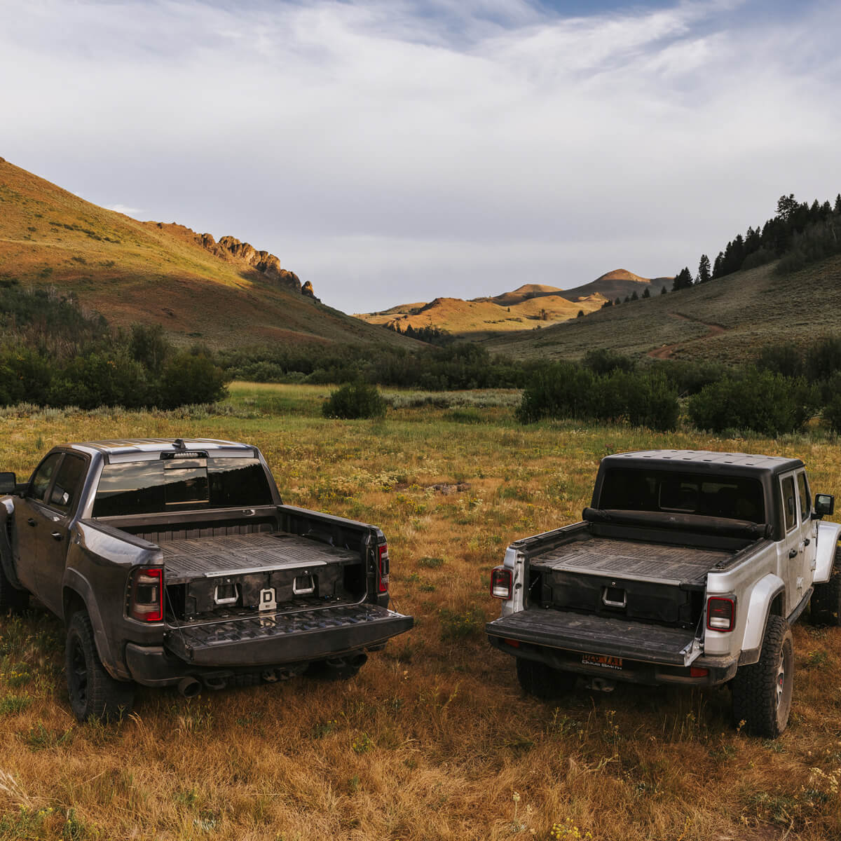 Two trucks parked in the mountains with drawer systems inside.