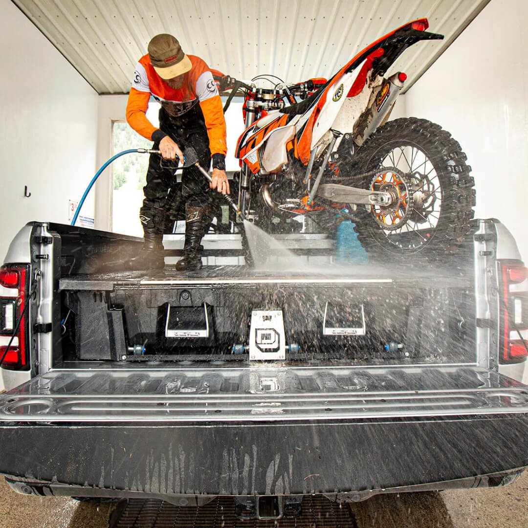 Man spraying a Drawer System with a power hose after dirt biking