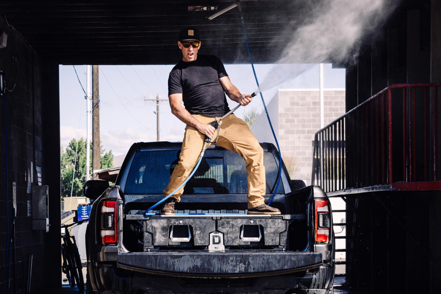 Decked's head of marketing standing on top of a drawer system spraying a car wash hose like a rockstar.