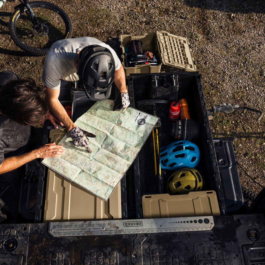 Overhead view of two mountain bikers mapping out where they will bike on the back of an open Drawer system