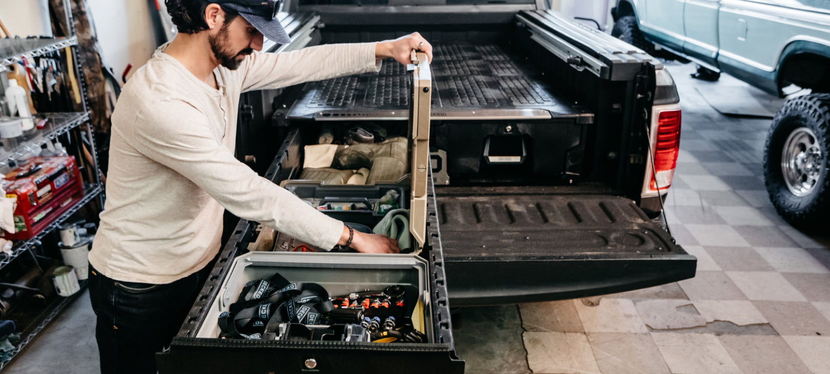 A man in his garage workshop retrieving gear from a D-co Case nested in his Rambox Drawer System.