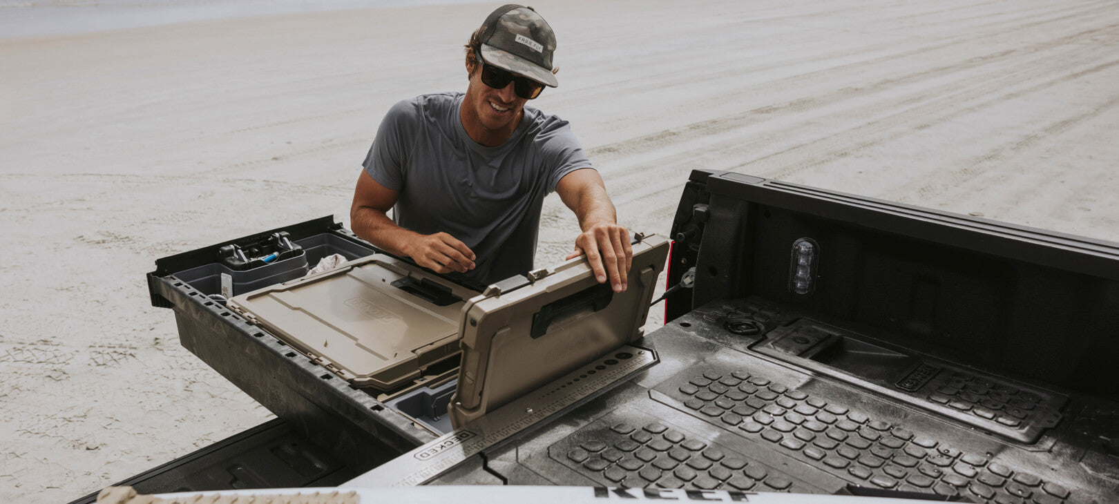 A man on a beach retrieving gear out of a D-co Case nested inside of his Drawer System.