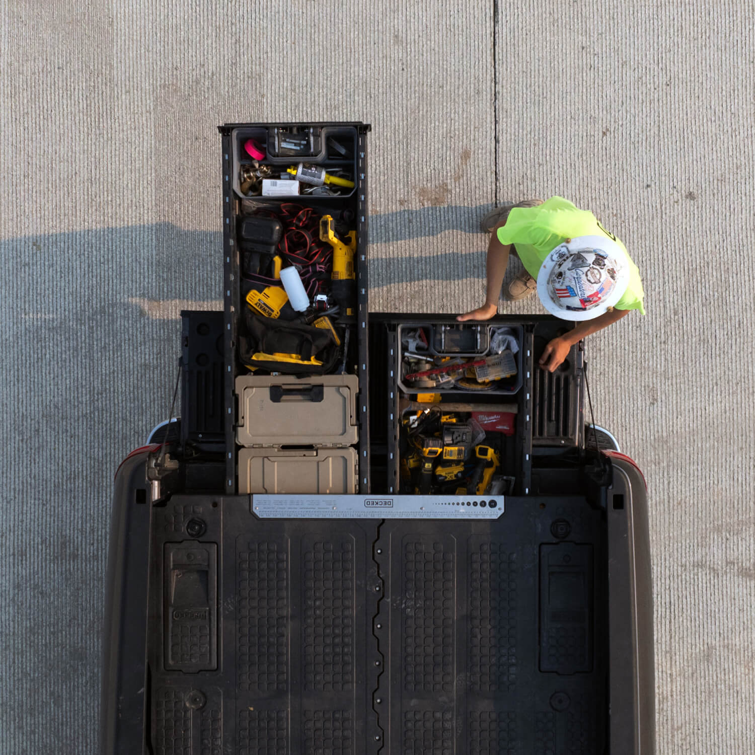 A bird's eye view of a  construction worker in a hard hat retrieving tools from his Drawer System.