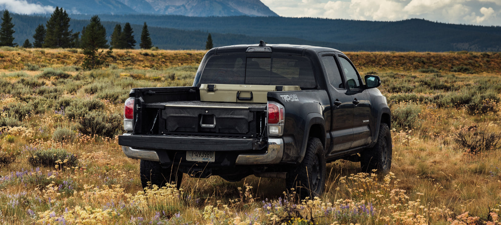 A truck parked in the mountains with its tailgate dropped to reveal its Drawer System with Minuteman D-co Case sitting on the deck.