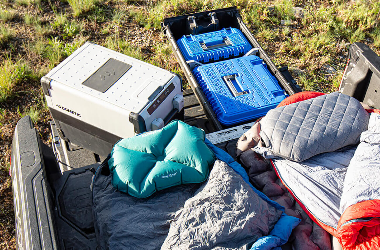Overhead view of sleeping bags on top of a drawer system and camping gear organized 