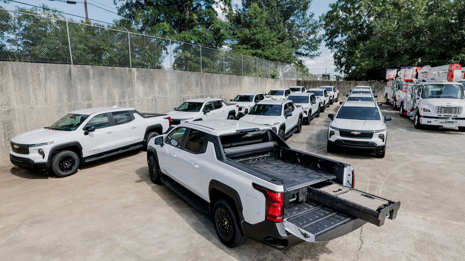Row of white pickup trucks with an open Drawer System in a lot.