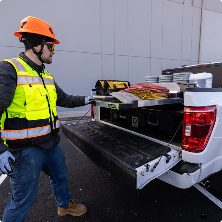 Person in safety gear loading tools into a truck bed