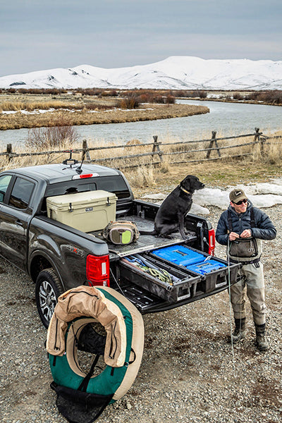 back of truck with a decked drawer system and a person going fly fishing