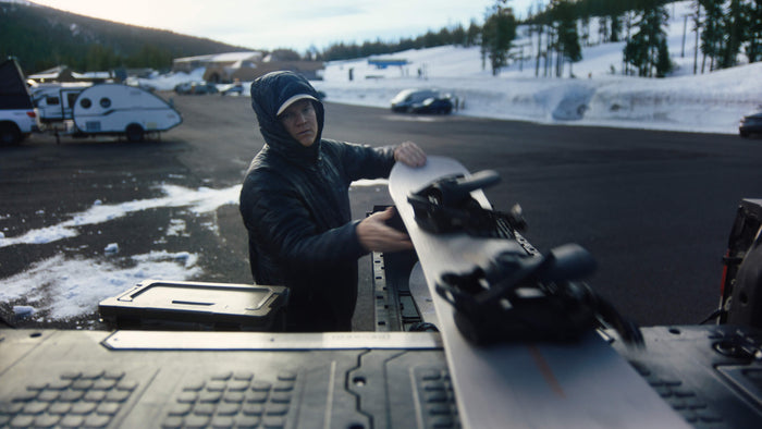 A guy in a ski resort parking lot pulling a snowboard off of the top of his DECKED drawer system