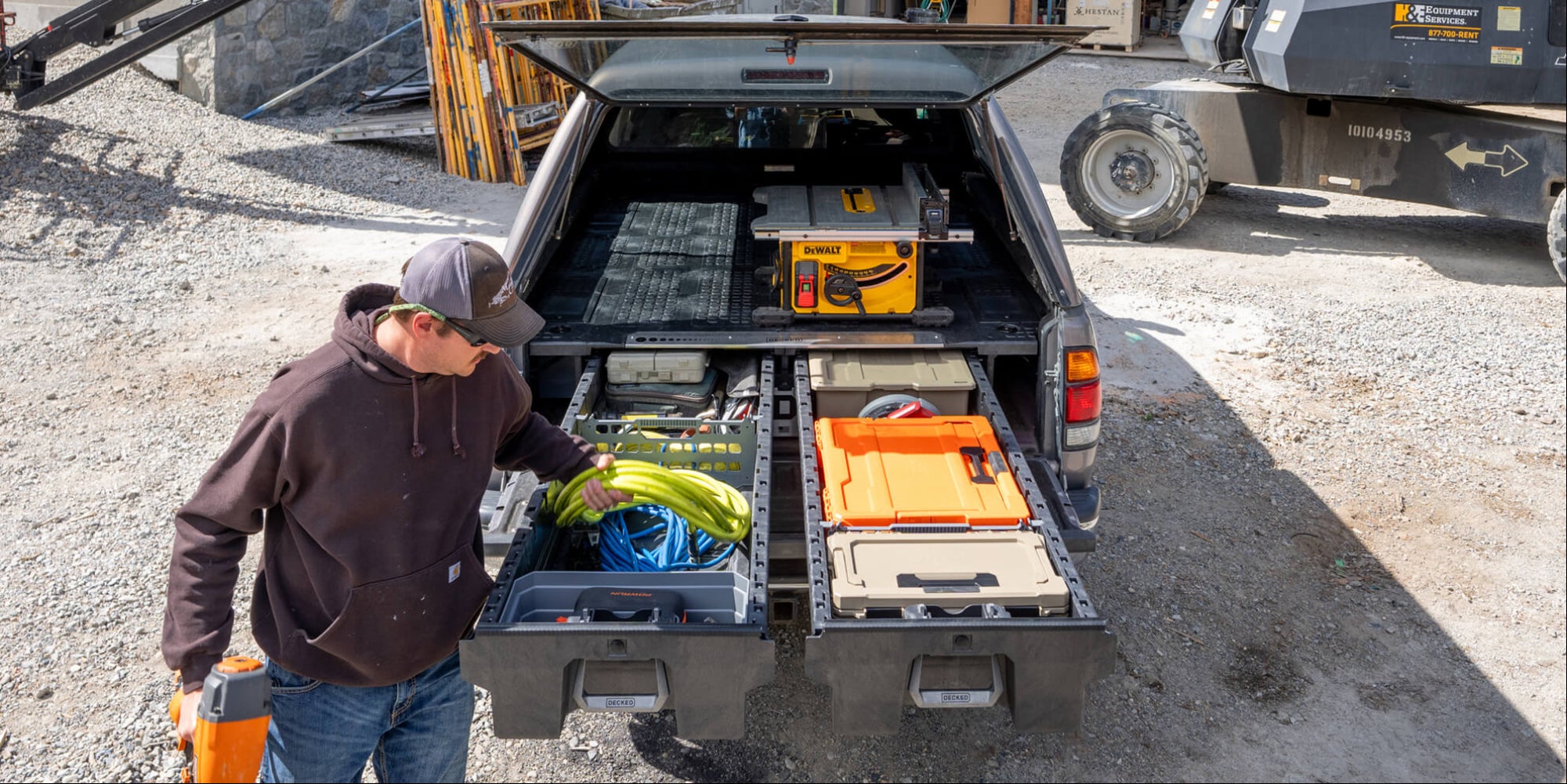 A man at his jobsite pulling gear out of the DECKED Drawer System in his Gen 1 Tundra.