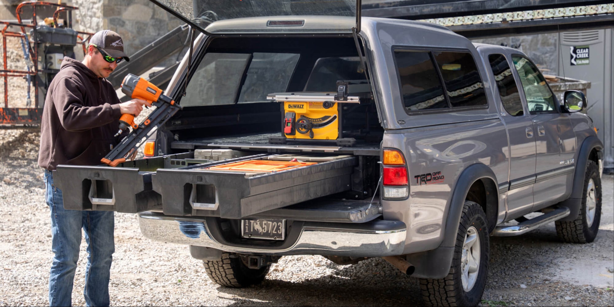 A man pulling a nail gun out of the DECKED Drawer System in his Gen 1 Tundra.